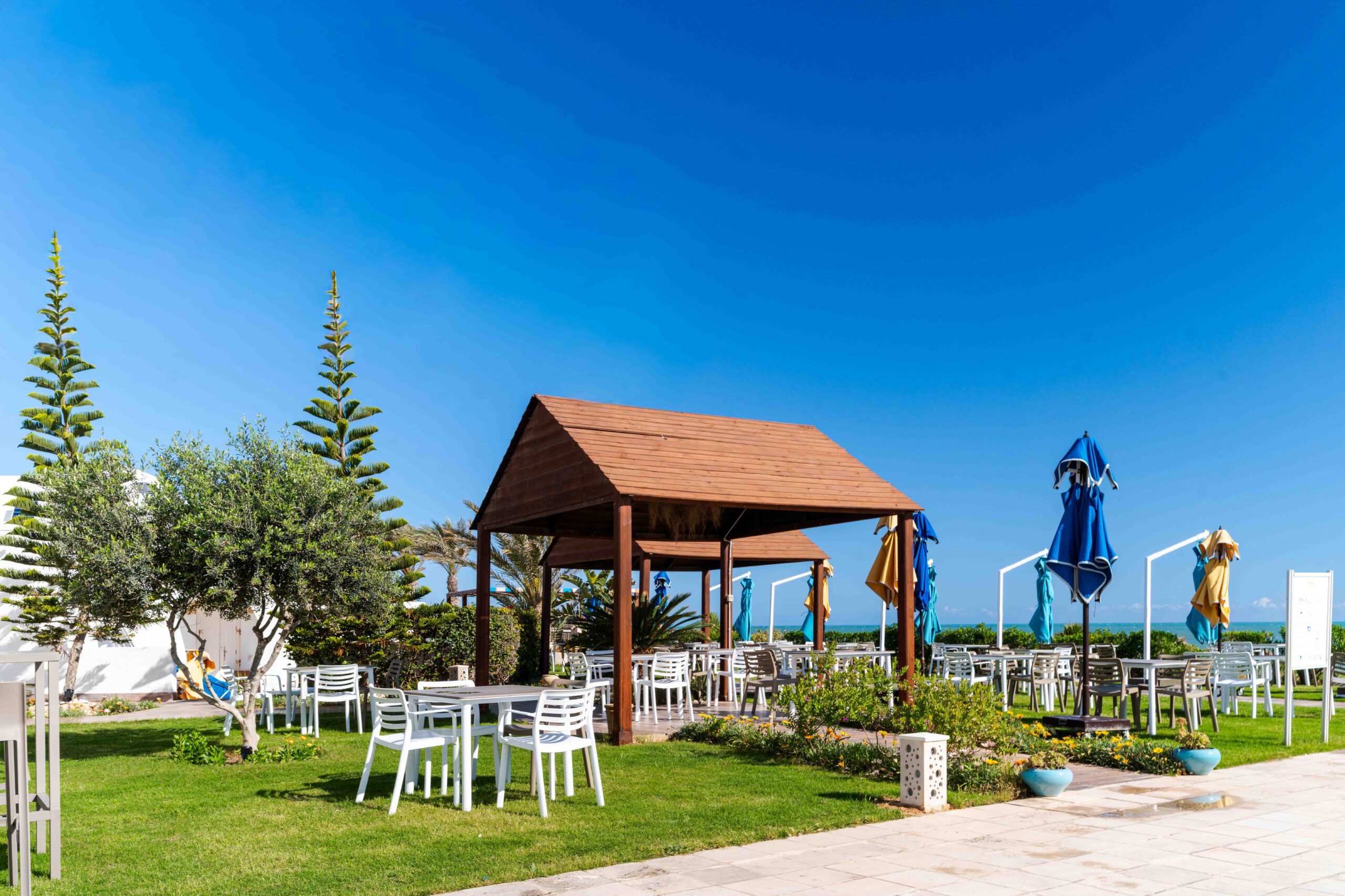 Terrasse du restaurant ombragée par une pergola en bois avec tables et chaises