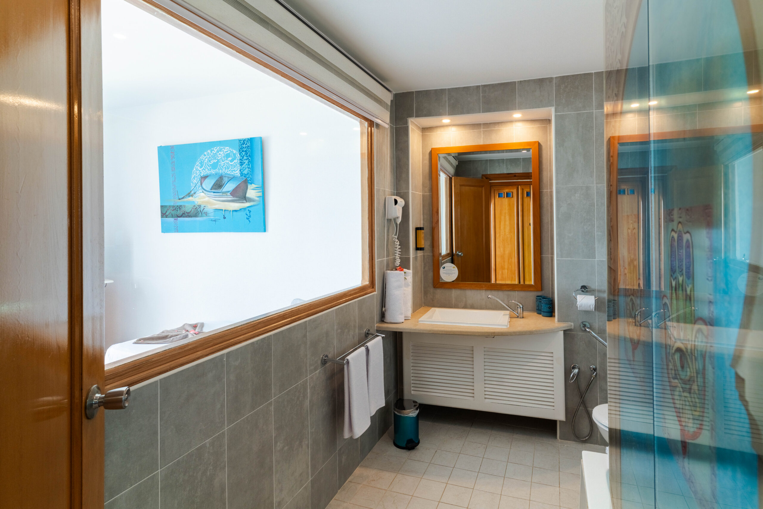 Salle de bain avec vasque, grand miroir en bois et tableau décoratif