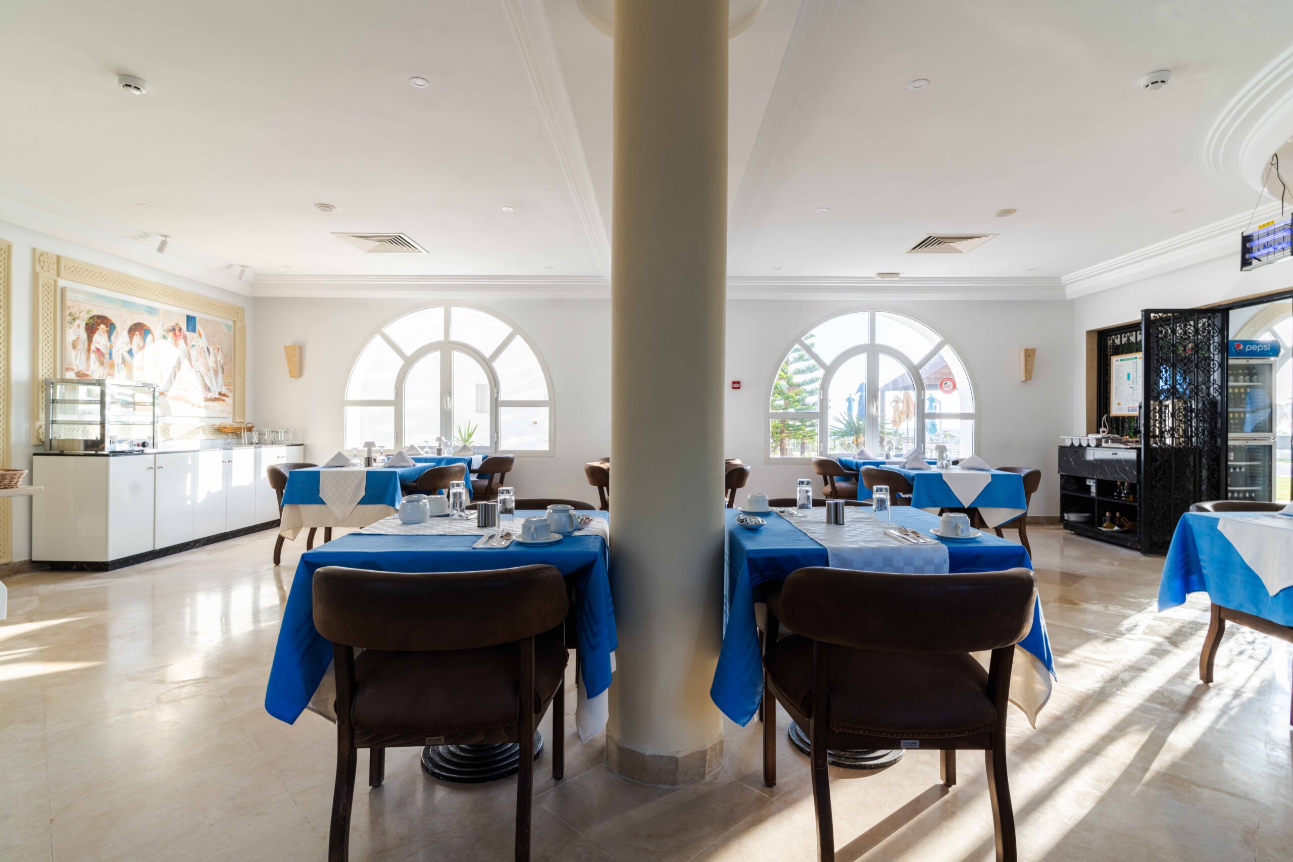 Salle de restaurant aux nappes bleues et fenêtres en arc