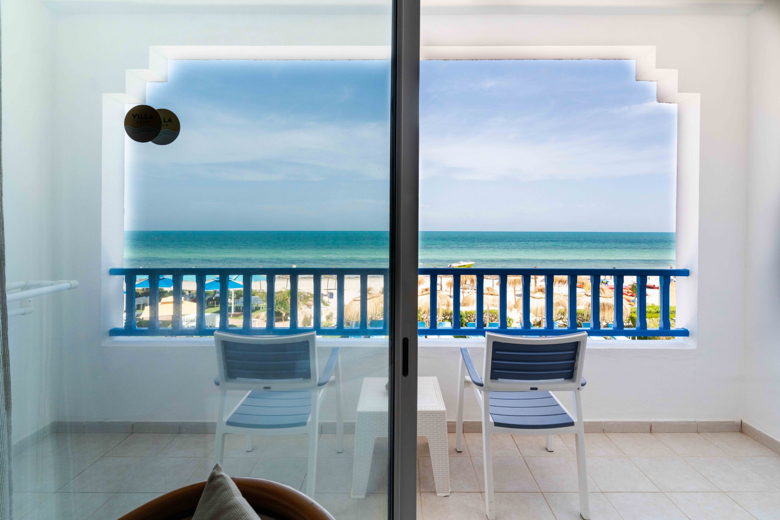 Balcon avec deux chaises face à la mer et aux parasols de plage