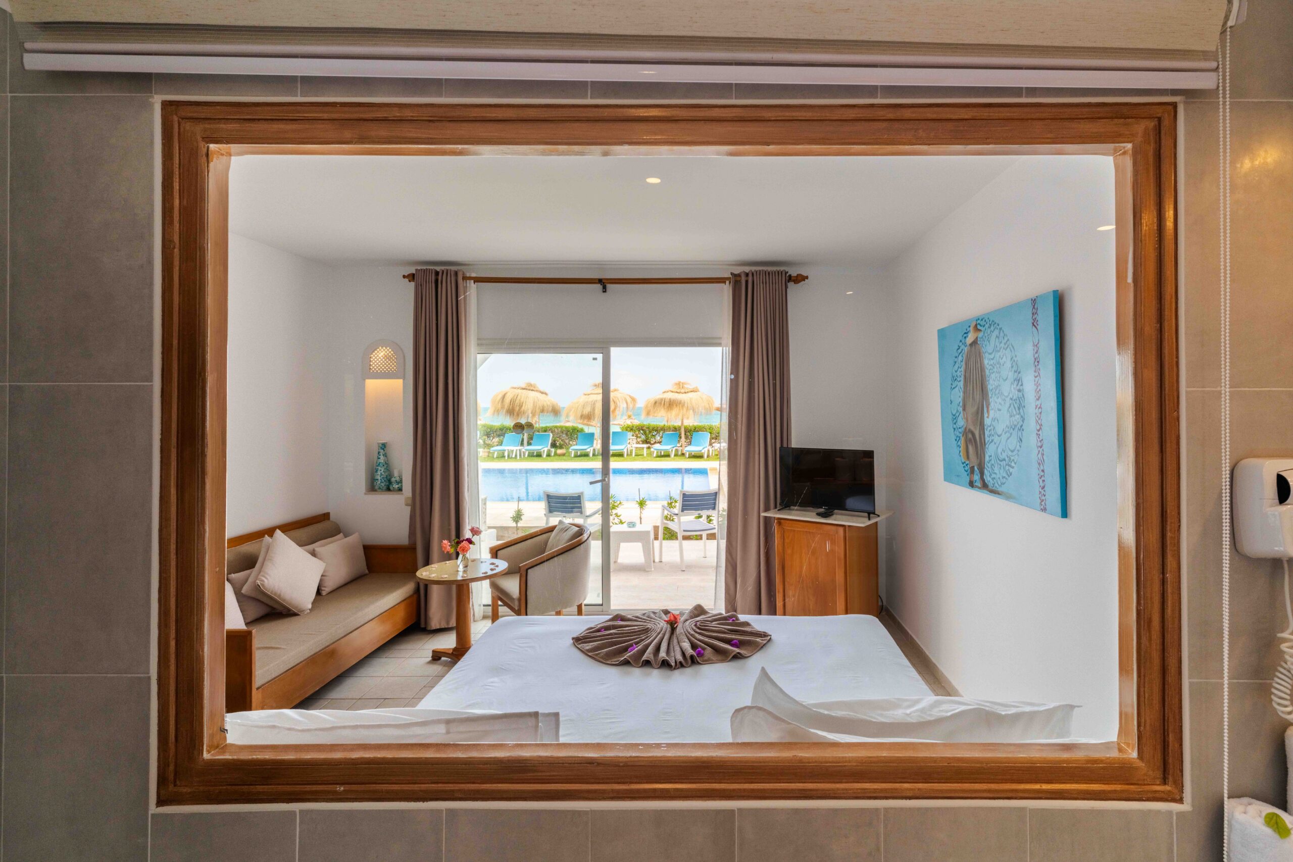 Chambre avec lit et salon donnant sur la piscine et la mer