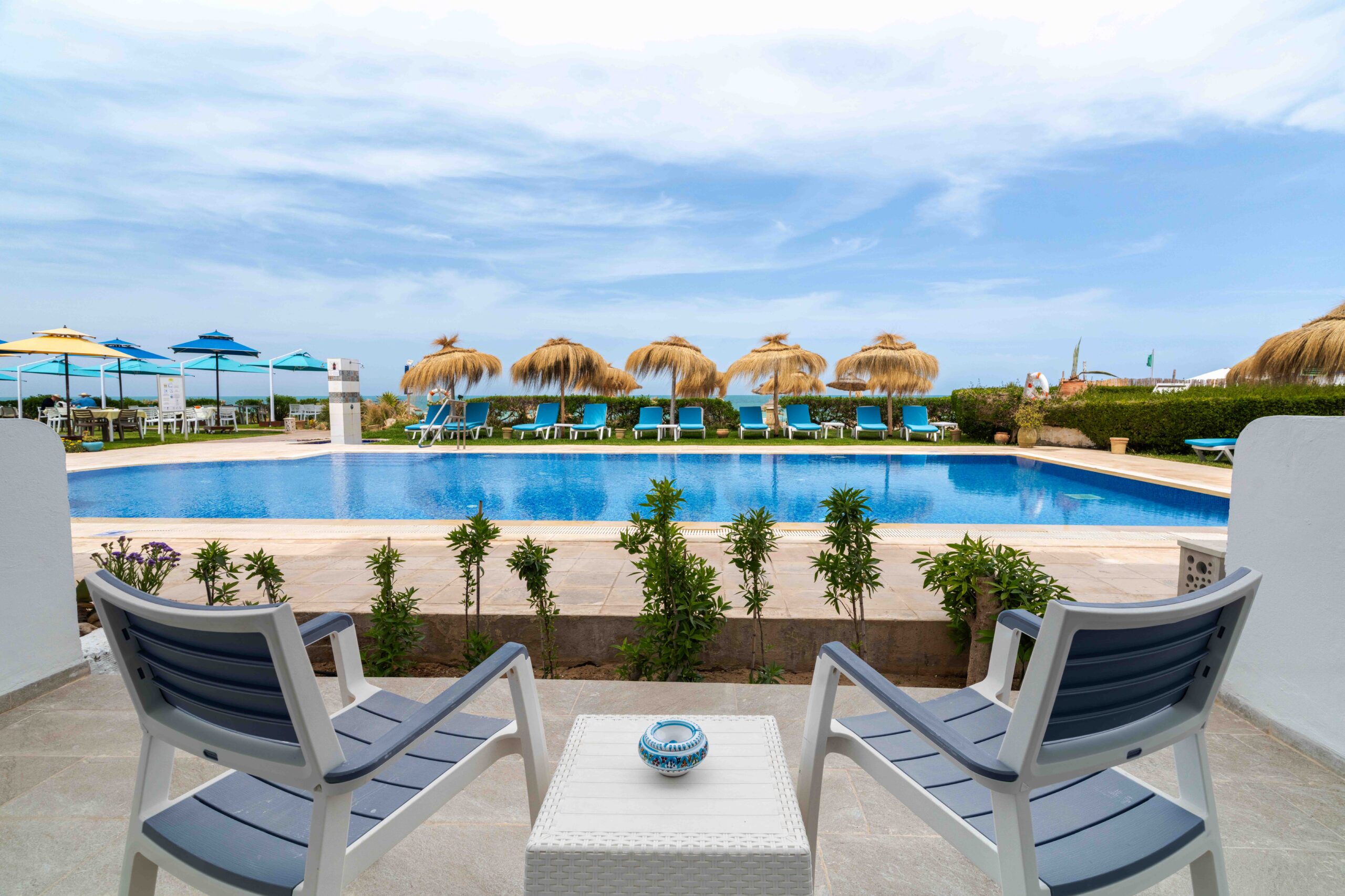 Coin salon extérieur avec vue sur la piscine et le littoral